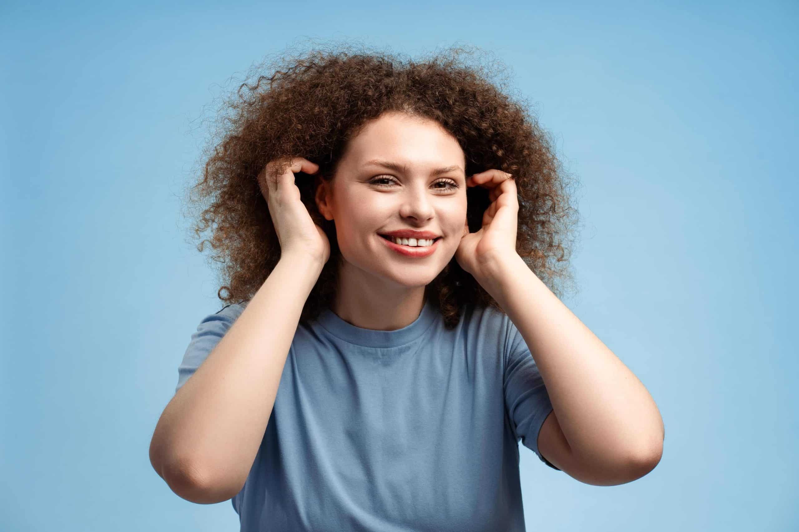 imgi 902 cheerful beautiful young woman with curly hair straightens her hairstyle looking in mirror free photo scaled - فن آذرخش